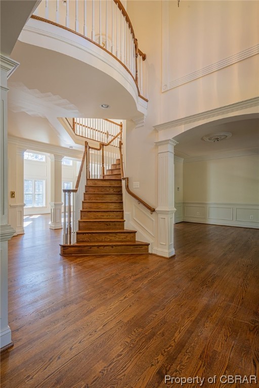 Stairs featuring ornamental molding, dark hardwood / wood-style flooring, a high ceiling, and ornate columns- dining room to the right in picture