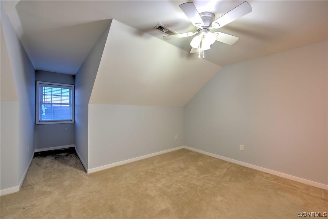 Additional living space featuring lofted ceiling, ceiling fan, and light colored carpet