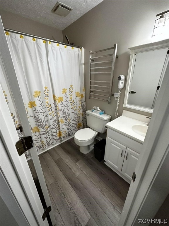 Bathroom featuring wood-type flooring, radiator, vanity, a textured ceiling, and toilet