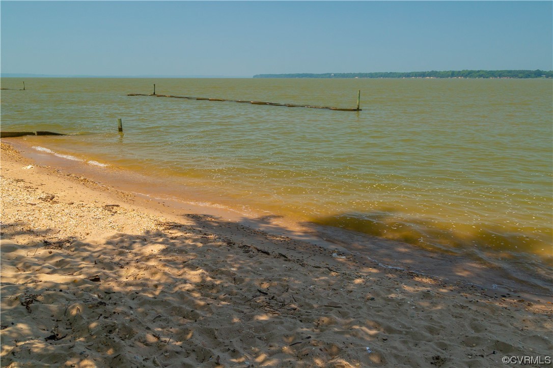 Property view of water featuring a dock and a beach view