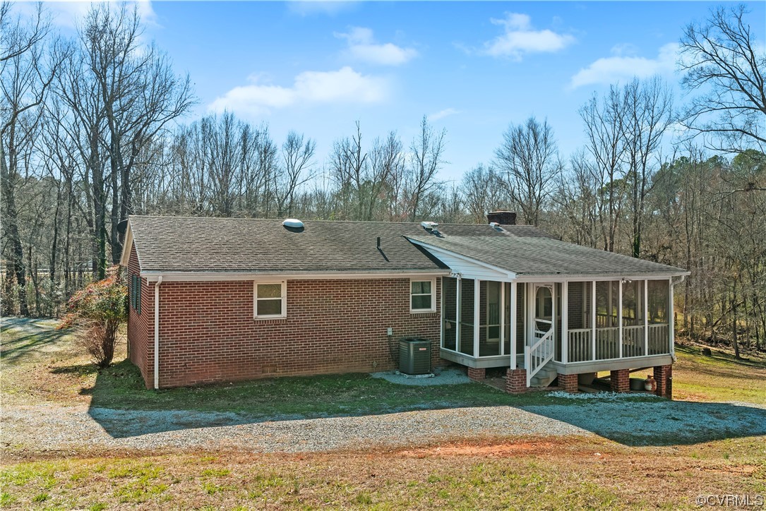 Rear view of property with a yard, a sunroom, and central AC