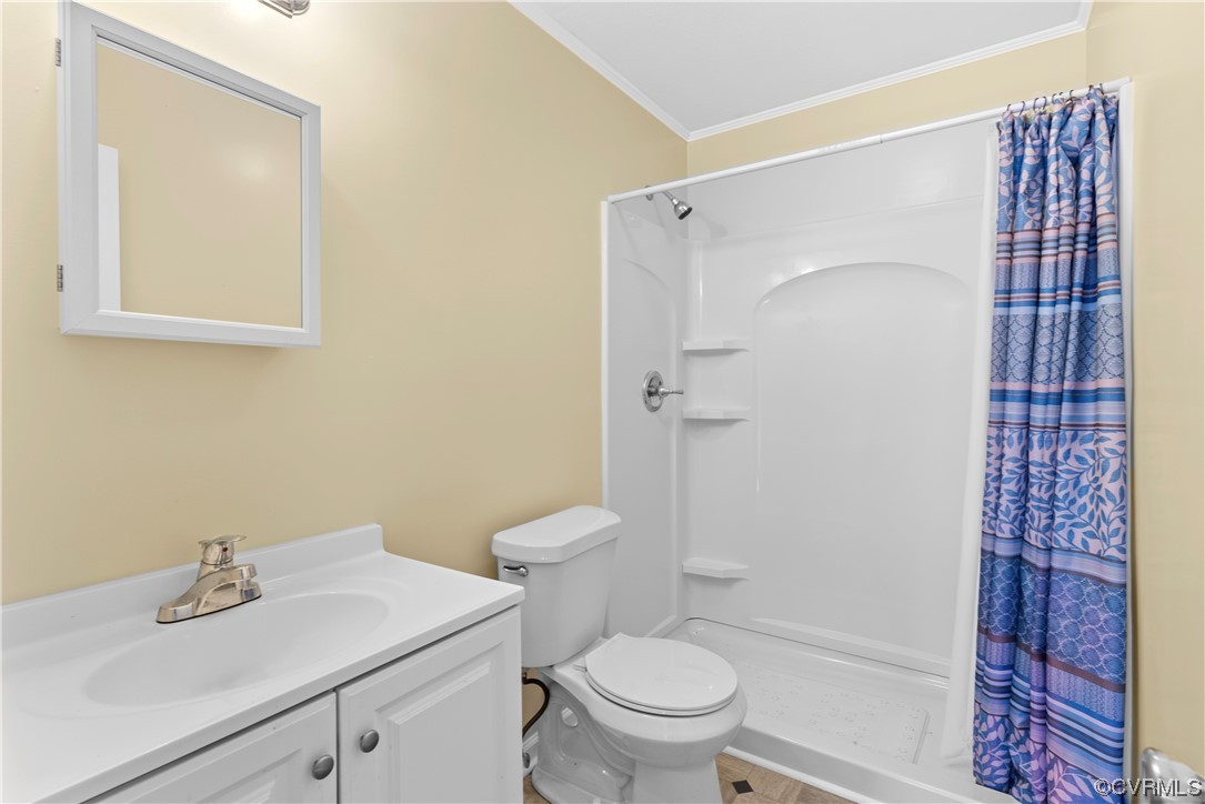 Bathroom with curtained shower, ornamental molding, vanity, toilet, and tile floors