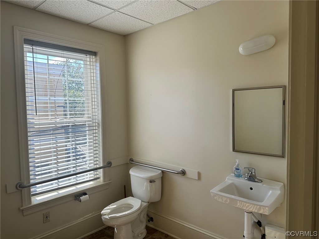 Bathroom featuring tile flooring, sink, toilet, and a drop ceiling