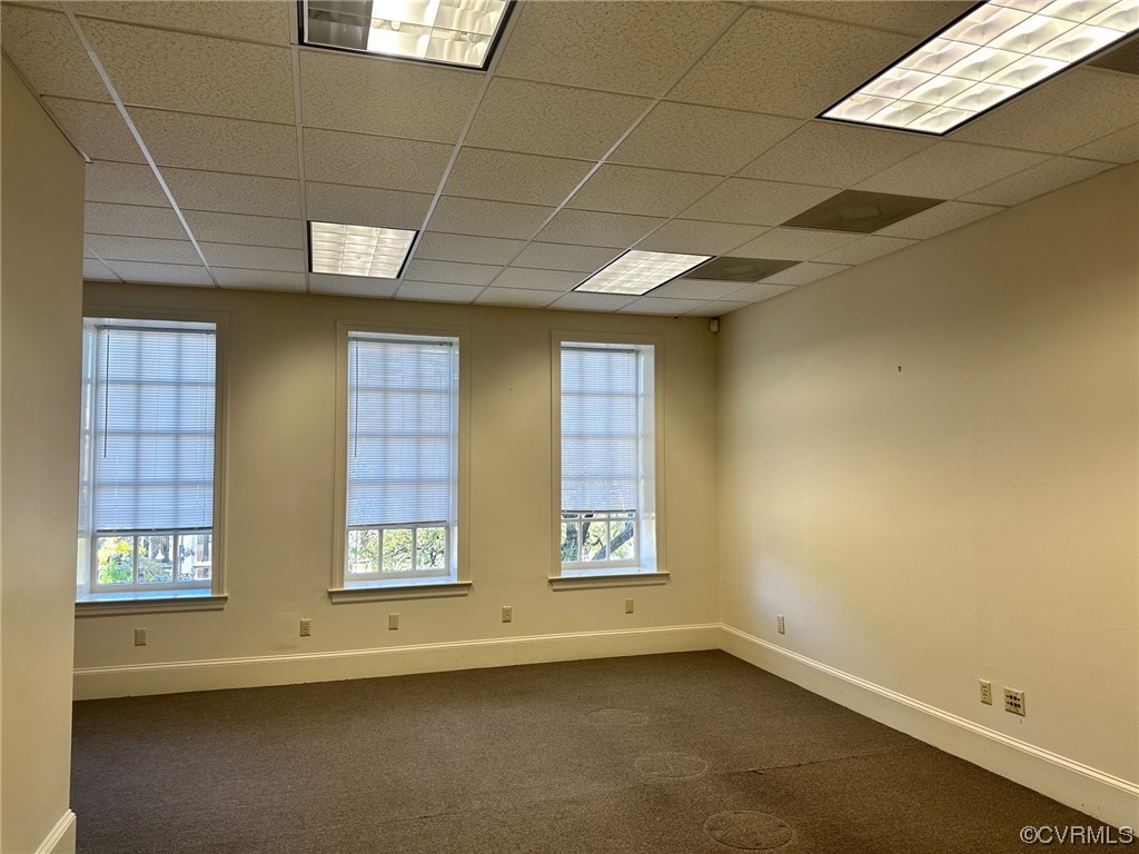Unfurnished room featuring a paneled ceiling and dark carpet
