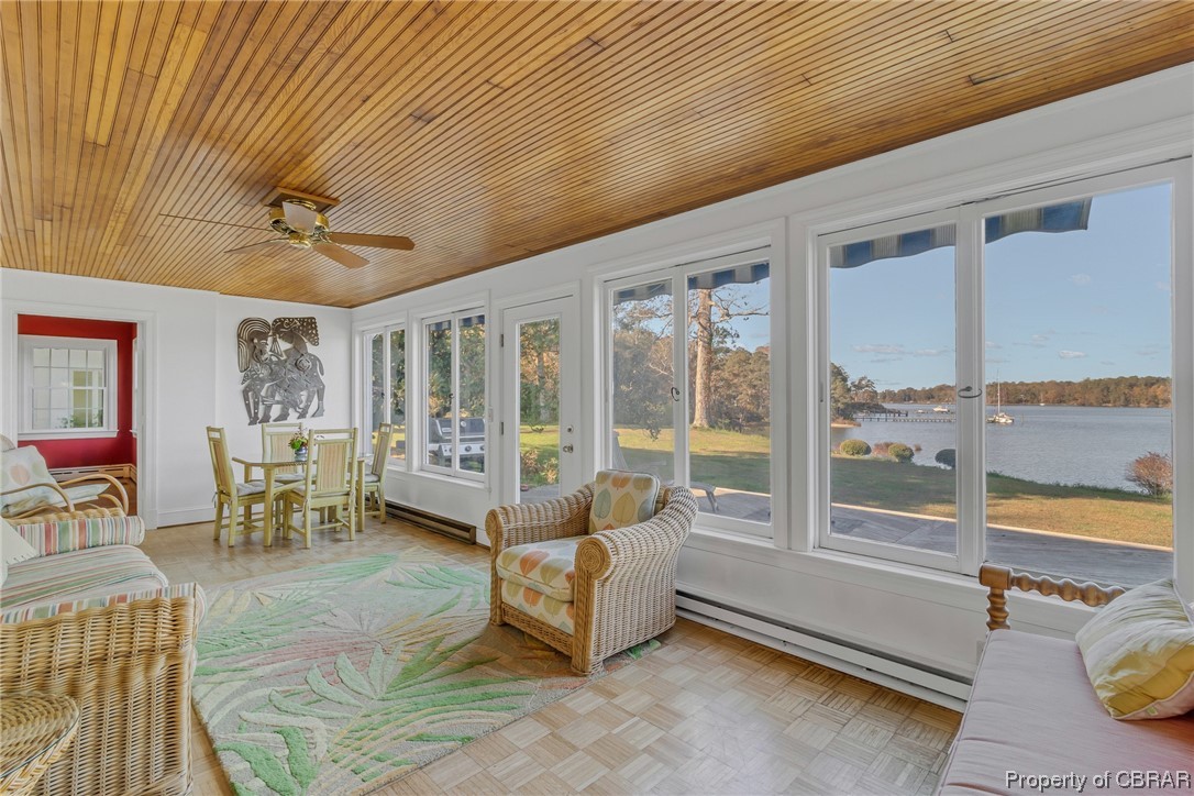 Sunroom featuring a water view, wooden ceiling, ceiling fan, and baseboard heating