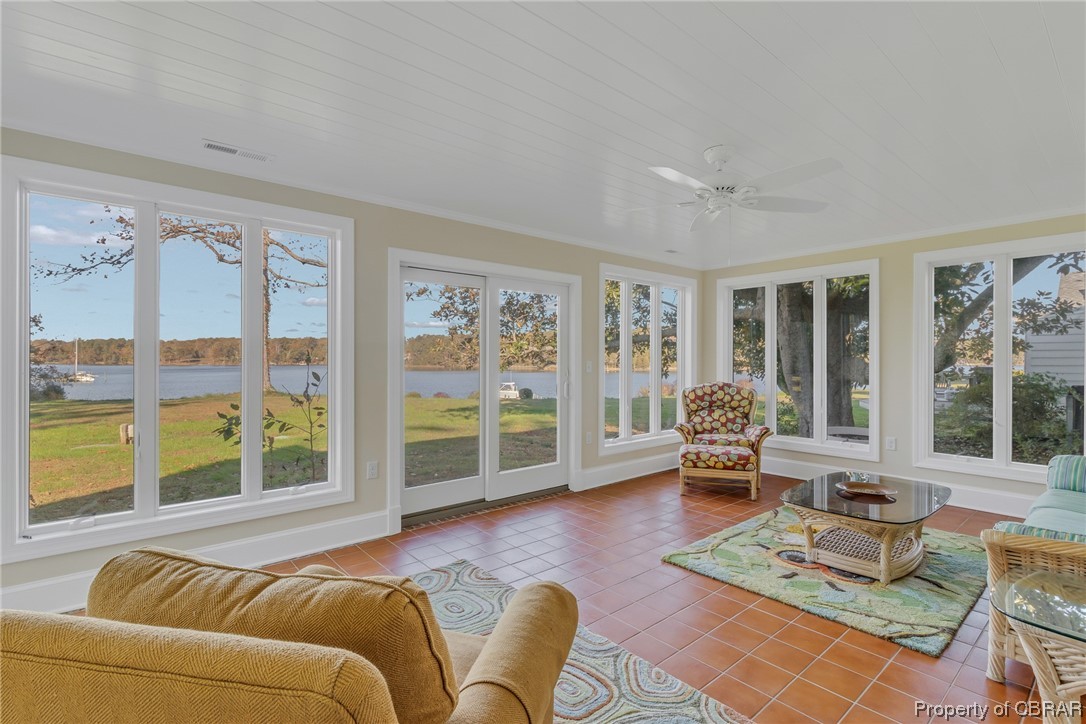 Sunroom / solarium featuring a water view and ceiling fan