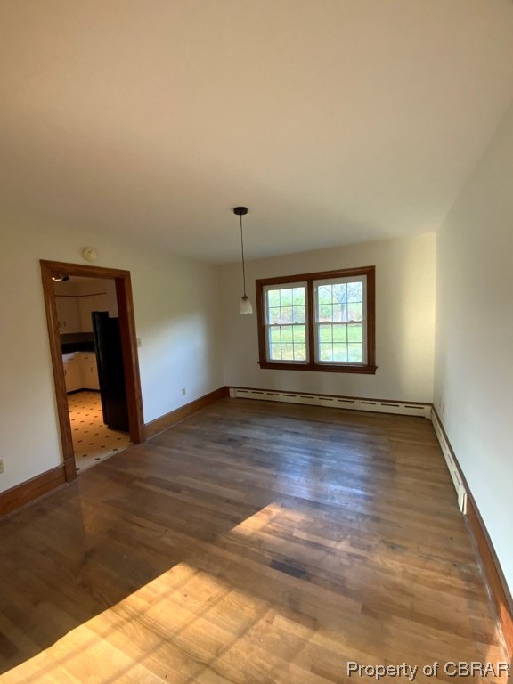 Unfurnished room featuring a baseboard radiator and dark hardwood / wood-style floors