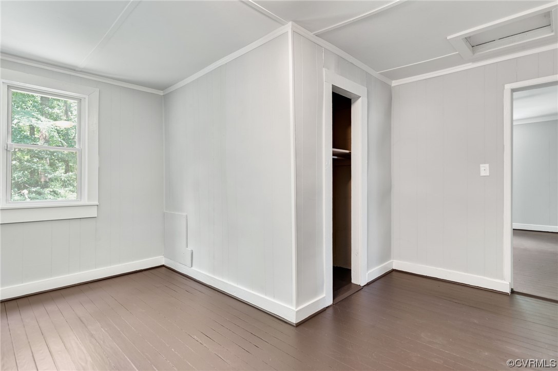 Unfurnished bedroom featuring crown molding and dark hardwood / wood-style floors