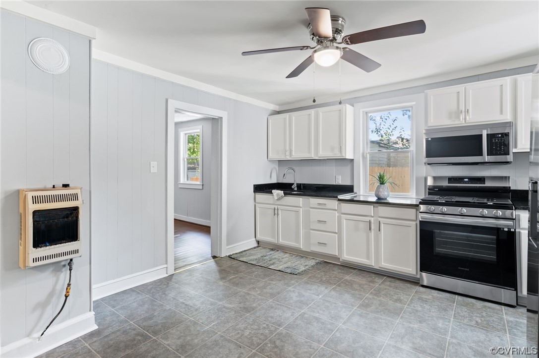 Kitchen with sink, white cabinets, stainless steel appliances, light tile flooring, and ceiling fan