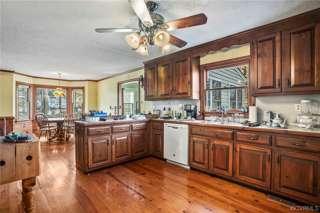 Kitchen with a textured ceiling, hardwood / wood-style flooring, white dishwasher, pendant lighting, and ceiling fan