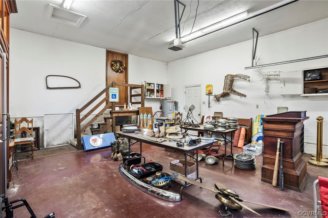 Garage with a workshop area, water heater, and a garage door opener