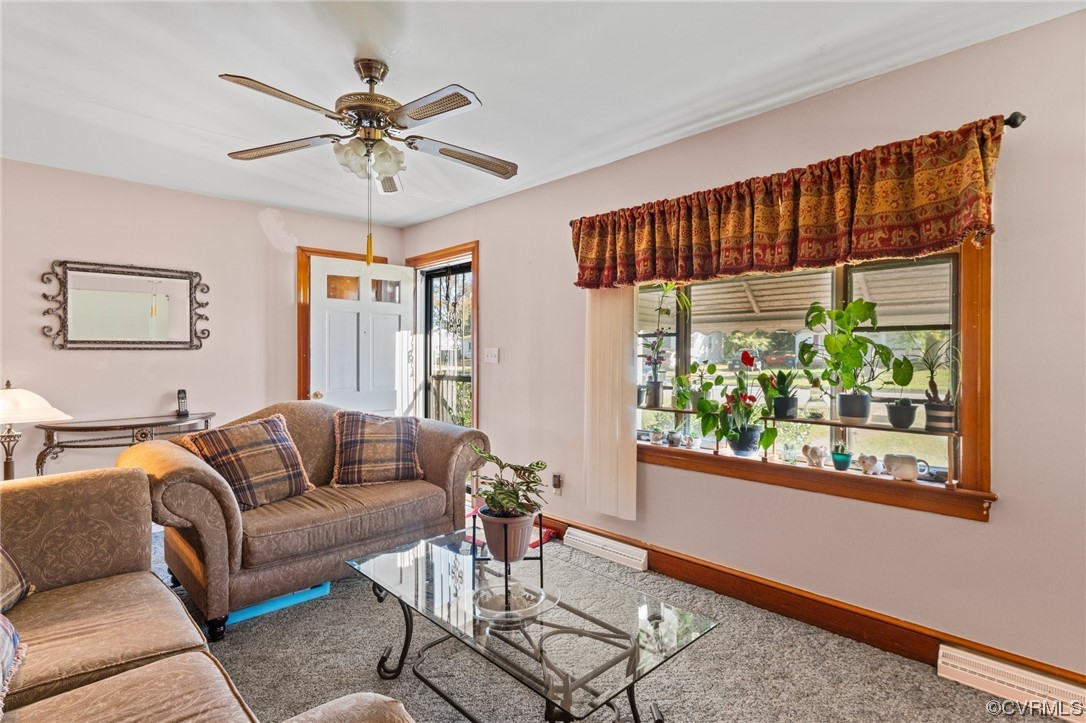 Carpeted living room with ceiling fan and a baseboard heating unit