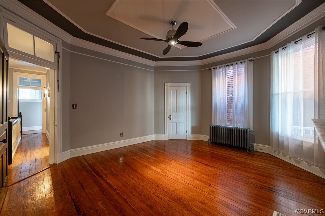 Bedroom with dark hardwood / wood-style floors, a tray ceiling, and radiator heating unit