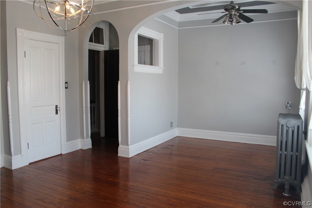 Bedroom featuring radiator, ceiling fan with notable chandelier, hardwood floors, and crown molding
