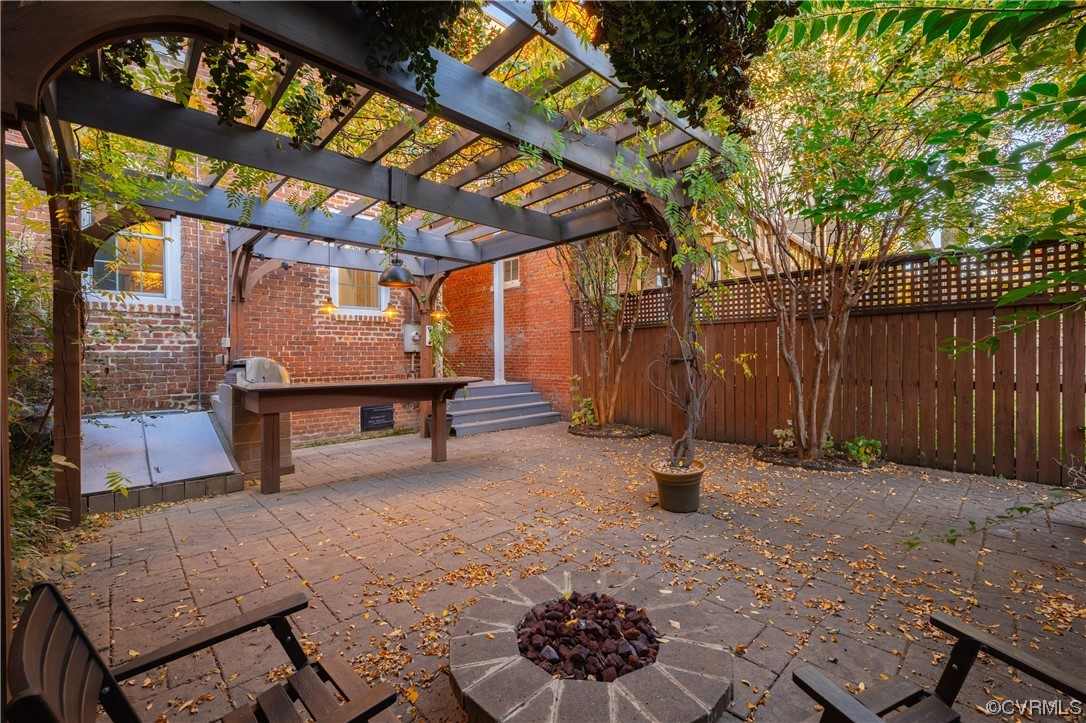 View of terrace with a pergola and a fire pit