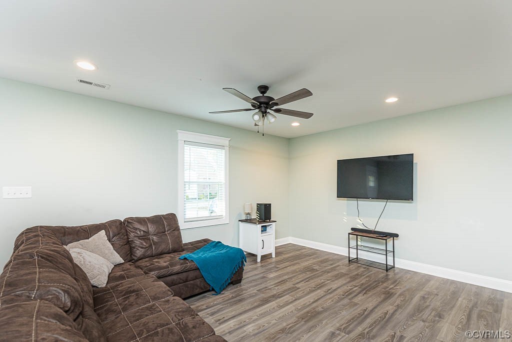 Living room featuring ceiling fan and dark wood-type flooring