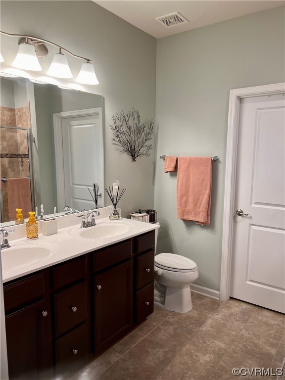 Bathroom with dual sinks, toilet, tile floors, and vanity with extensive cabinet space