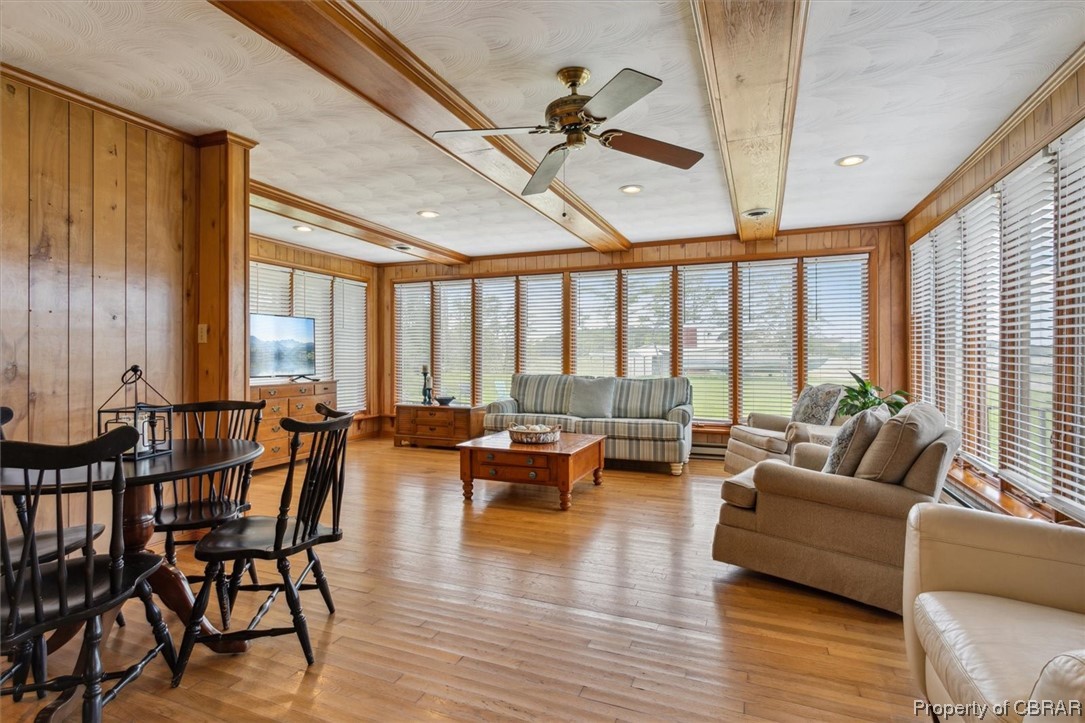 Living room featuring wooden walls, ceiling fan, plenty of natural light, and light hardwood / wood-style floors