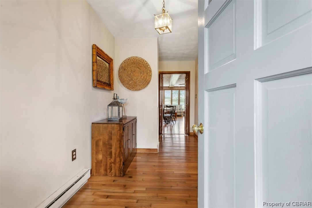 Hallway featuring light wood-type flooring and a baseboard heating unit