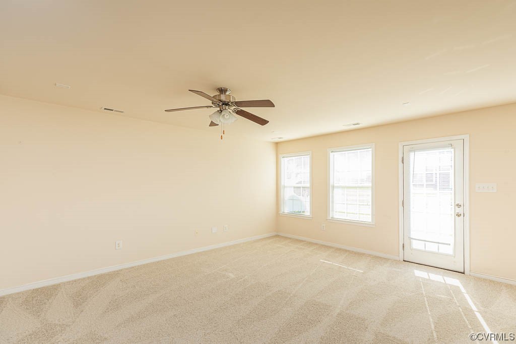 Unfurnished room featuring a healthy amount of sunlight, light carpet, and ceiling fan