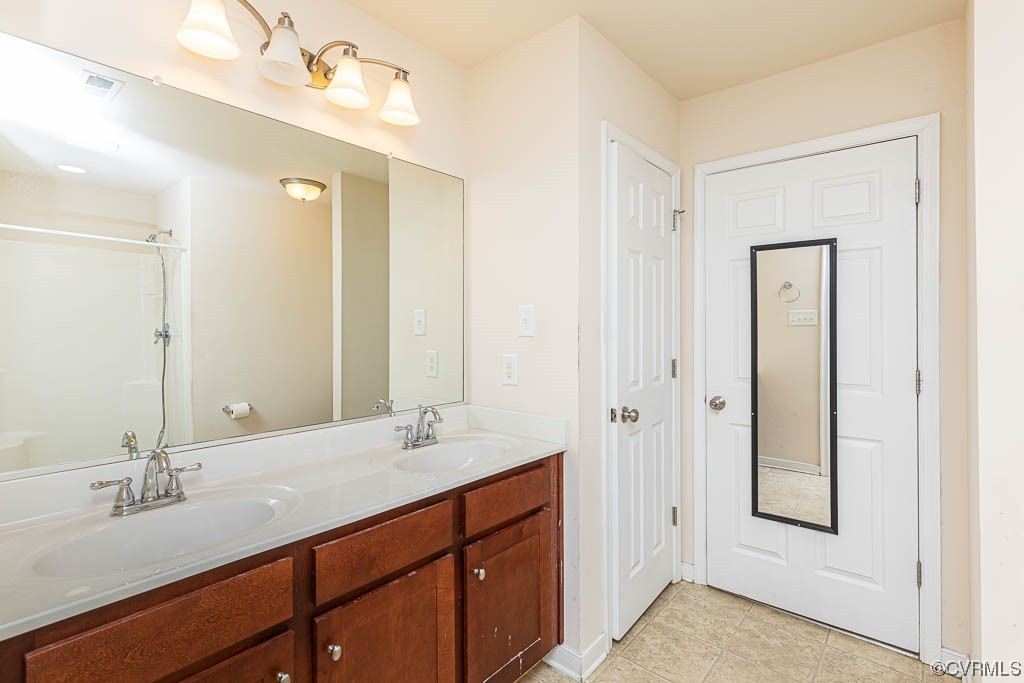 Bathroom featuring tile floors, oversized vanity, and dual sinks