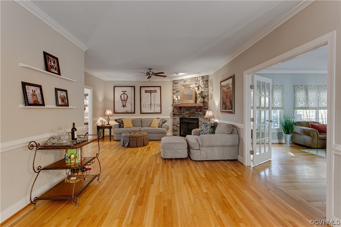 Family room featuring ceiling fan, gas fireplace, crown molding, and light hardwoodflooring