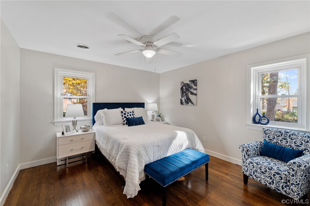 Bedroom with multiple windows, dark hardwood / wood-style floors, and ceiling fan