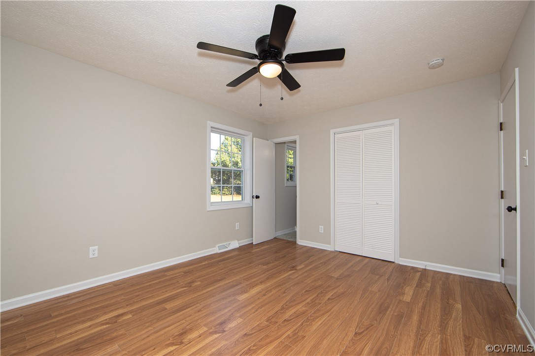 Unfurnished bedroom with light wood-type flooring, ceiling fan, and a closet