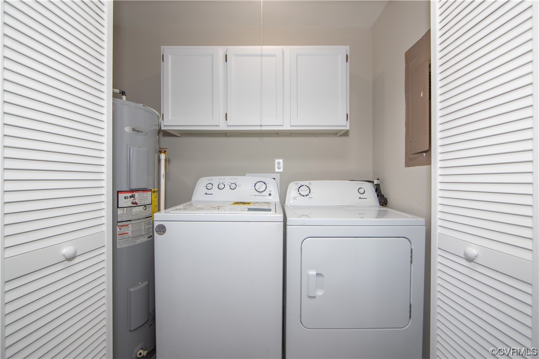 Laundry room featuring washing machine and clothes dryer, cabinets, and electric water heater