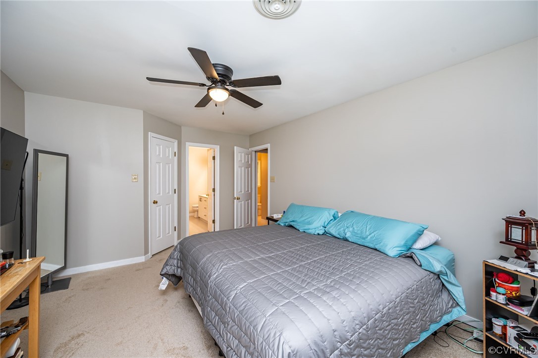 Bedroom with light carpet, ensuite bathroom, and ceiling fan