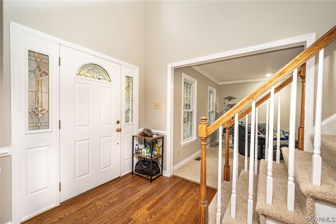 Foyer featuring dark wood-type flooring and crown molding