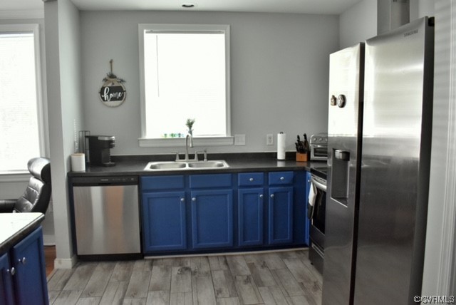 Kitchen featuring light wood-type flooring, sink, Dishwasher, Disposal and blue cabinets