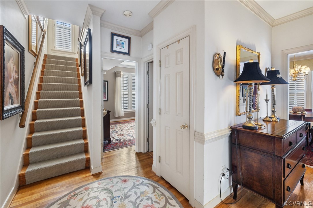 Foyer entrance with a notable chandelier, hardwood flooring, and crown molding