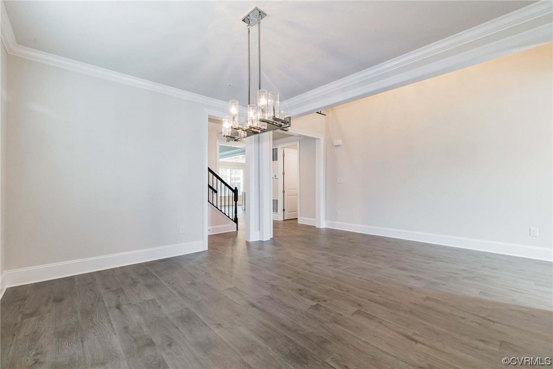 Unfurnished room featuring dark hardwood / wood-style floors, an inviting chandelier, and crown molding