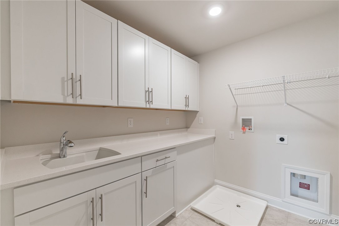 Laundry room with hookup for an electric dryer, cabinets, sink, and light tile floors