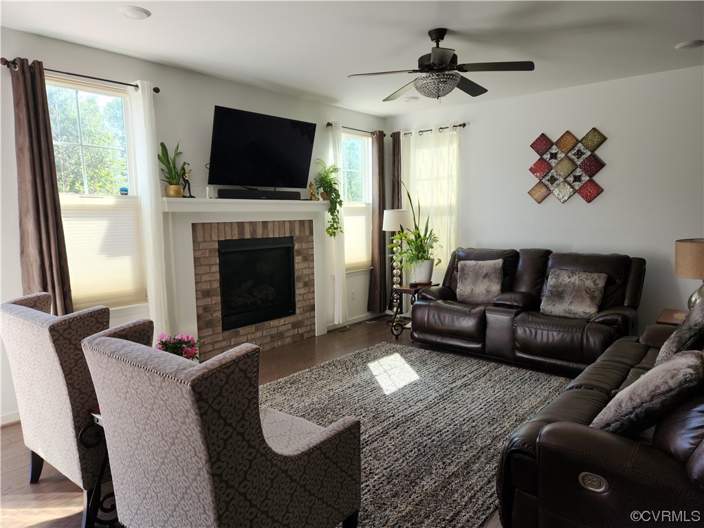 Living room featuring ceiling fan, a brick fireplace, and hardwood / wood-style floors