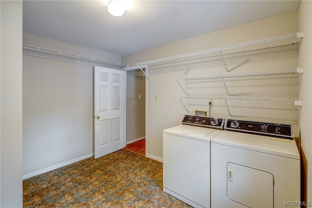 Clothes washing area featuring dark tile floors, hookup for a washing machine, and washing machine and dryer