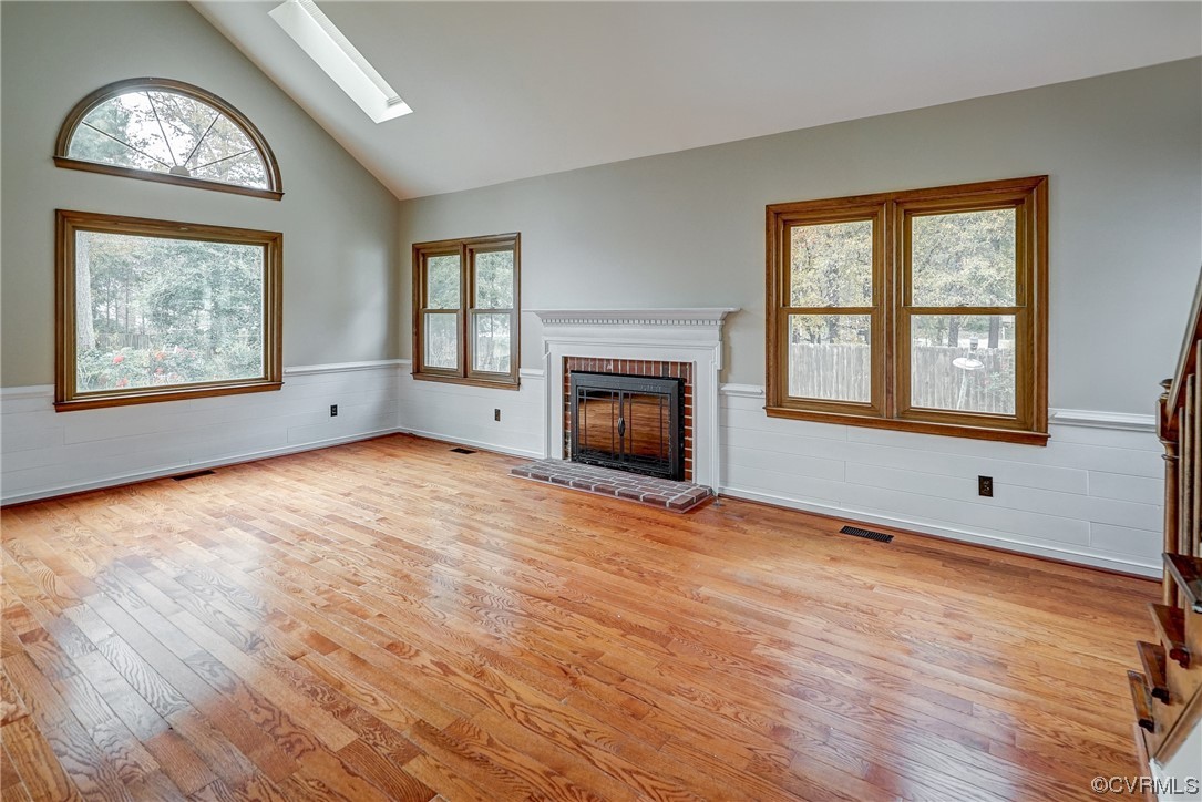 Family room with a wealth of natural light, a skylight, light hardwood / wood-style floors, and a fireplace