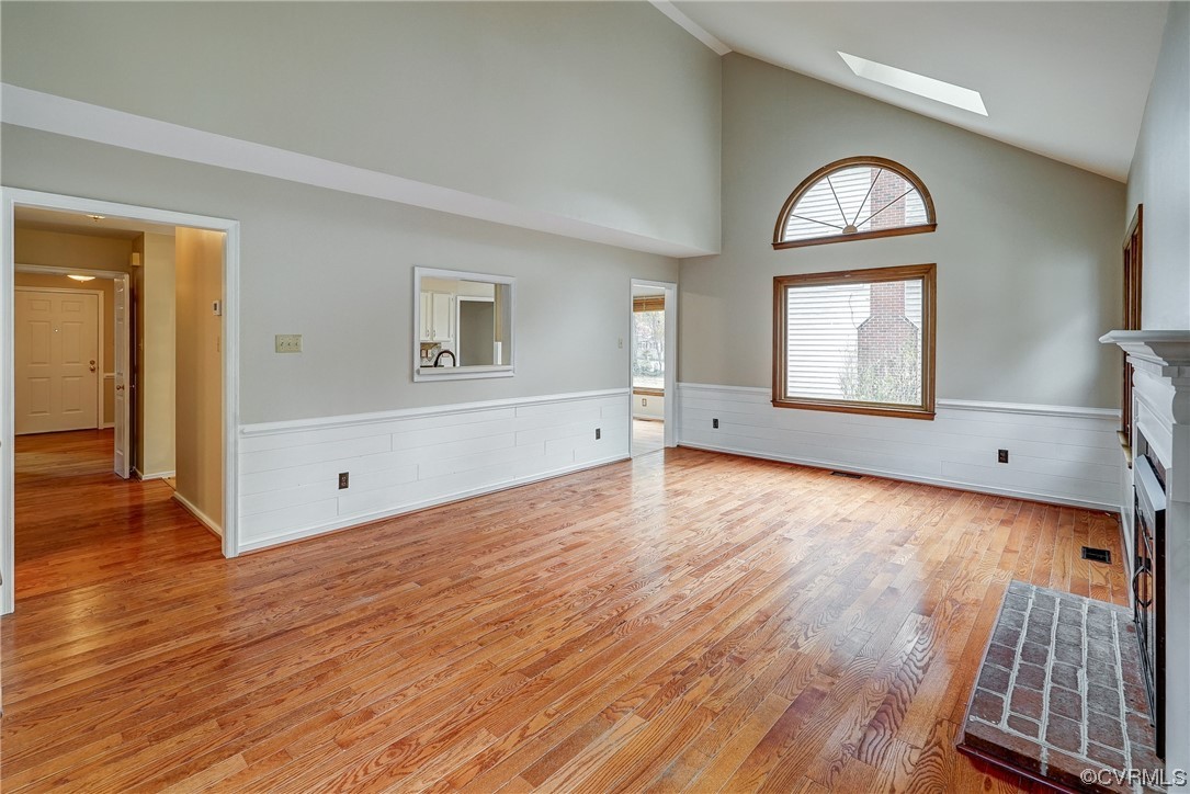 Family Room room with light hardwood / wood-style flooring, a skylight, and high vaulted ceiling