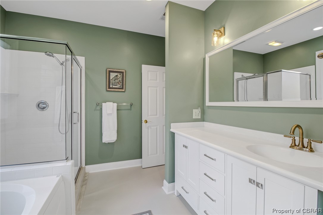 Primary bath with independent shower, jetted tub, tile flooring, and vanity with extensive cabinet space