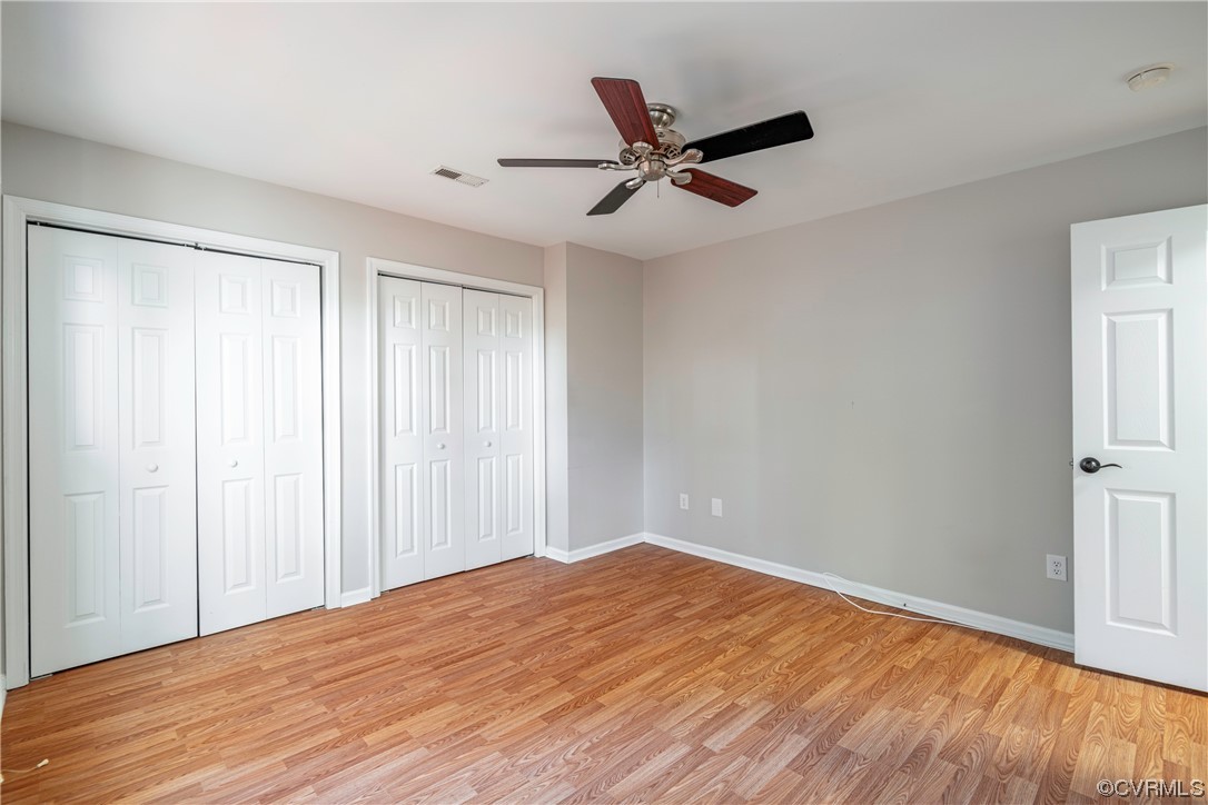 Unfurnished bedroom featuring multiple closets, ceiling fan, and light hardwood / wood-style floors