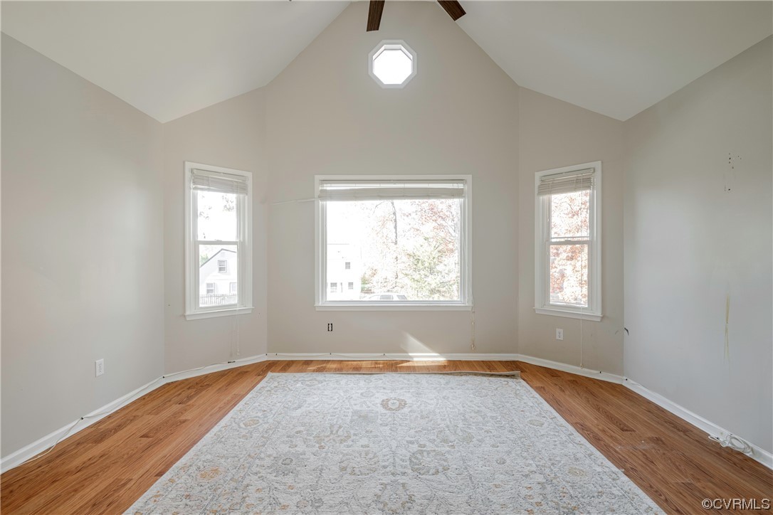 Spare room featuring ceiling fan, light wood-type flooring, and vaulted ceiling