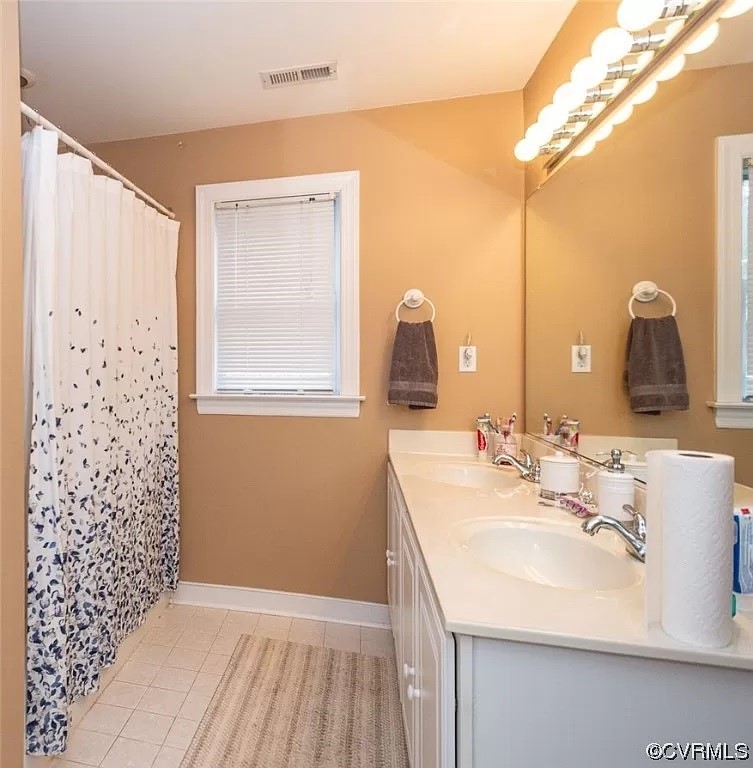 Bathroom with double sink, tile flooring, and large vanity