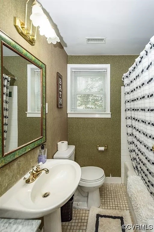 Full bathroom with shower / bath combo with shower curtain, tile floors, sink, and toilet