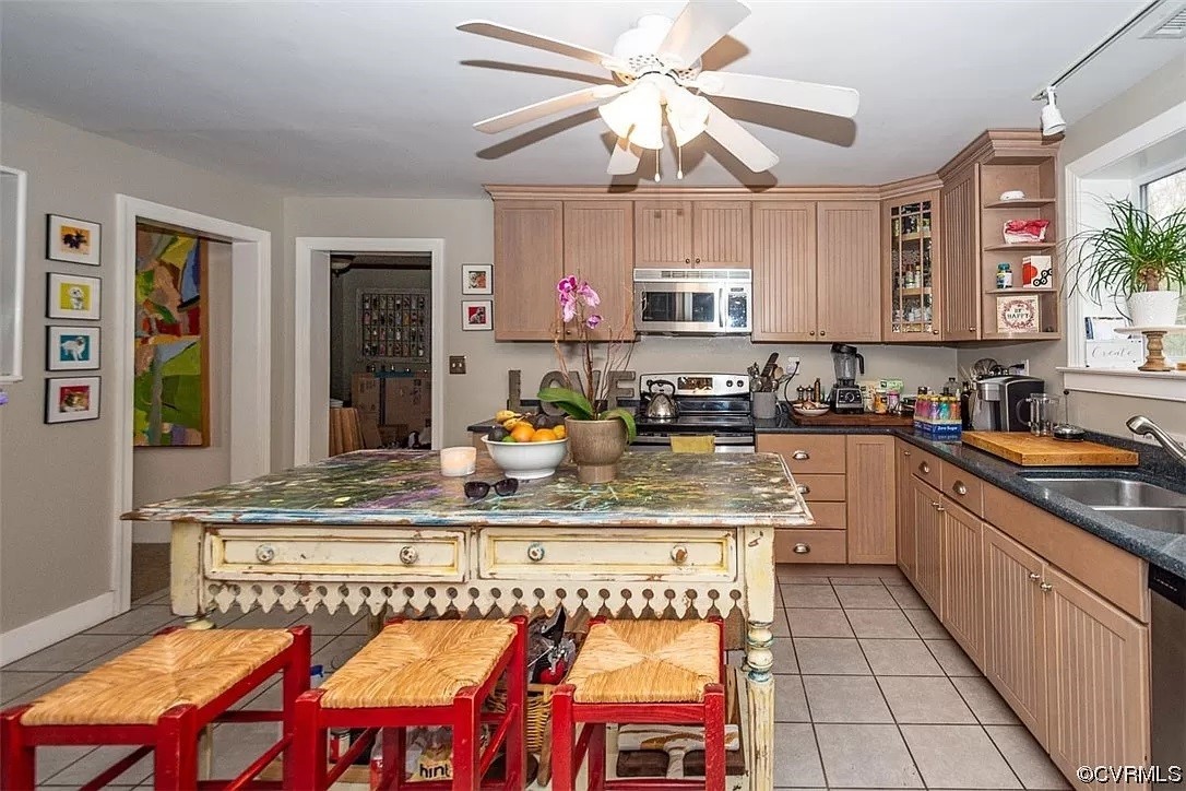 Kitchen featuring sink, stainless steel appliances, ceiling fan, light tile floors, and a kitchen island
