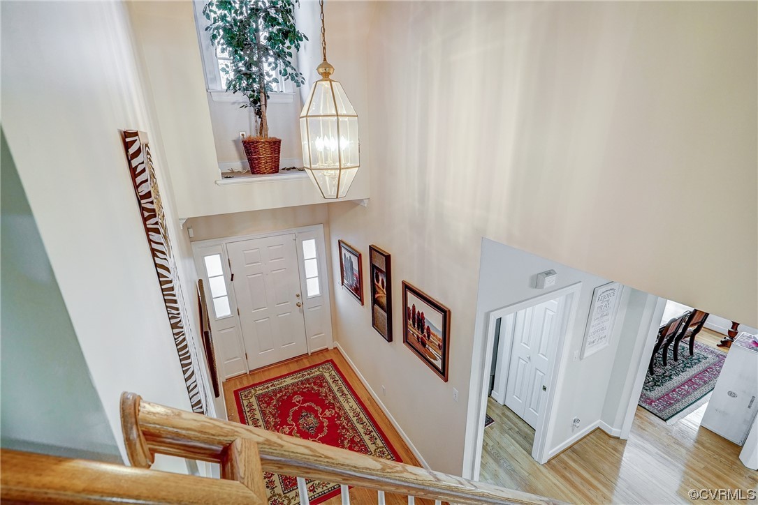 Entrance foyer with a towering ceiling, plenty of natural light, an inviting chandelier, and hardwood floors