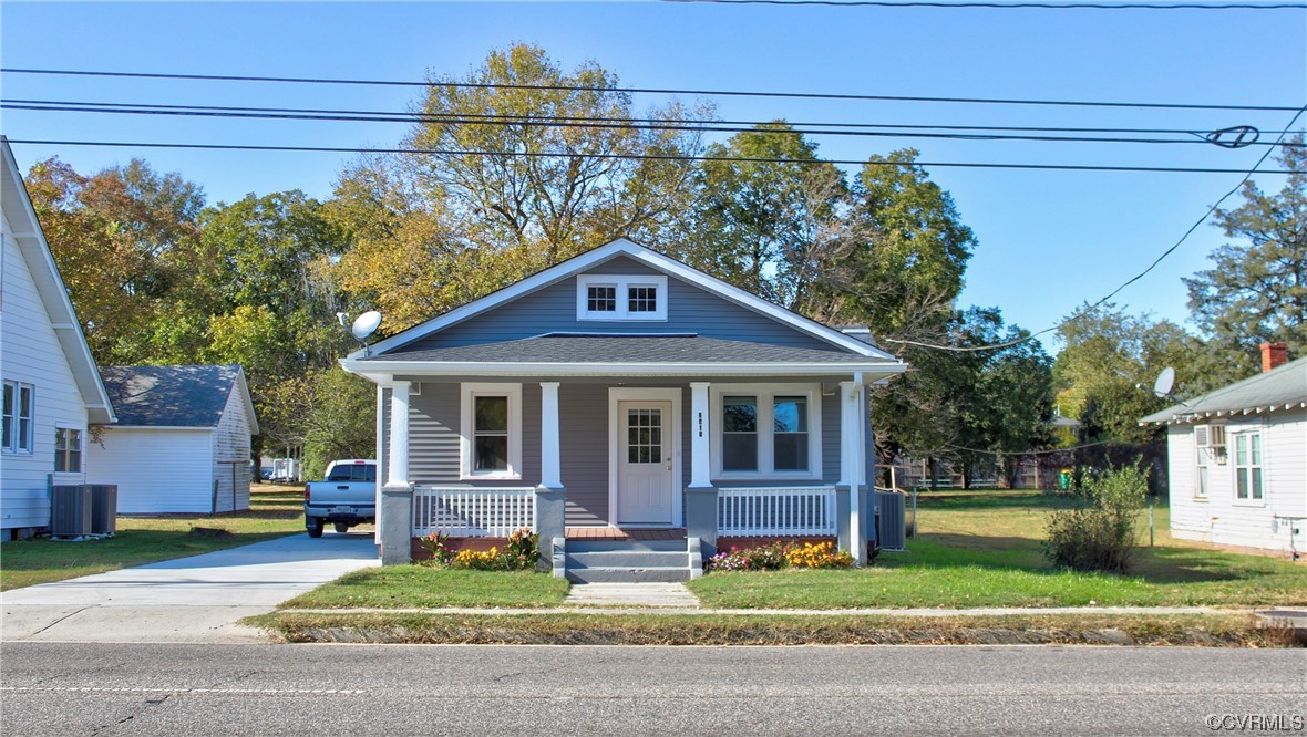 Bungalow-style home with a front yard, a porch, and central air condition unit