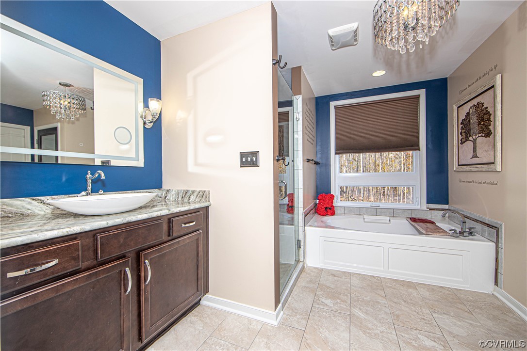Bathroom with a notable chandelier, plus walk in shower, oversized vanity, and tile flooring
