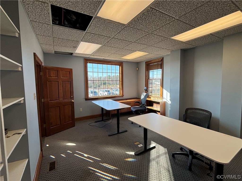 Office space with a paneled ceiling and dark carpet