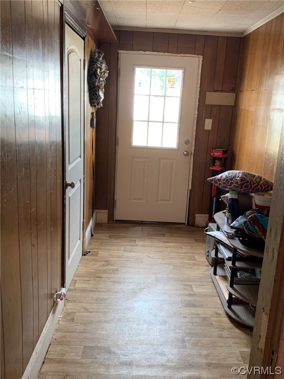 Doorway to outside featuring wood walls and light wood-type flooring; bedroom 2 to left and den entry to right in this picture; kitchen behind